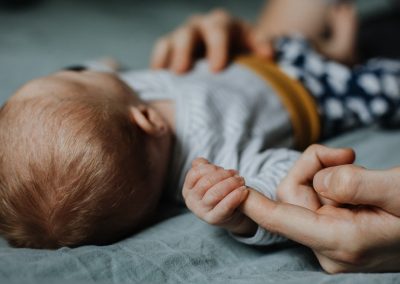 Schlafendes neugeborenes Baby, während eines Shootings in Aachen, hält mit ganzer Hand einen großen Finger fest