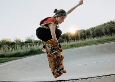 Frau mit Skateboard im Aachener Pool macht einen Trick in der Luft